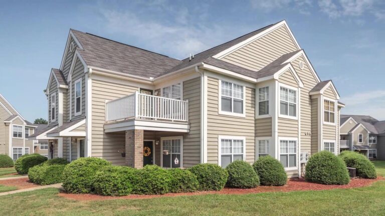 Exterior view of Mebane Mill apartment complex featuring landscaped grounds and well-maintained shrubs.
