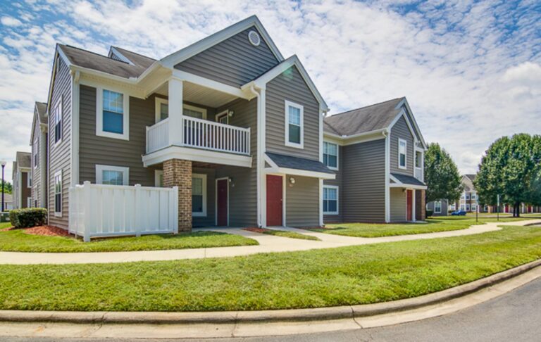 Apartment complex named Parkside Village, surrounded by green grass and trees.